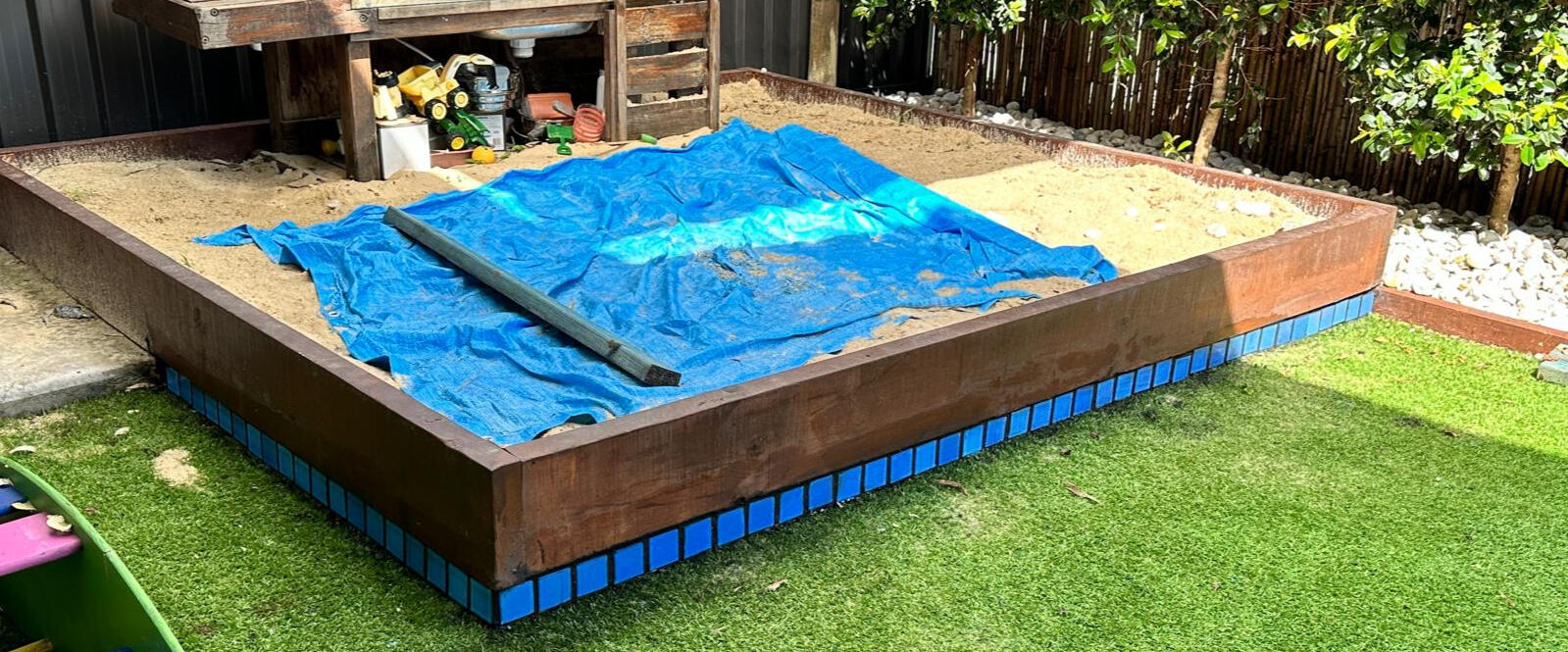 Custom timber-framed backyard sandbox with blue tile edging built by Brett Handyman in Noosa QLD
