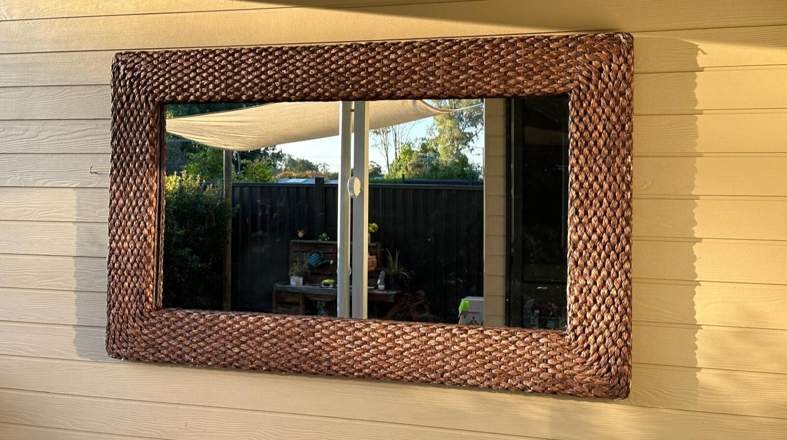 Woven-frame outdoor mirror professionally mounted on exterior wall in Noosa