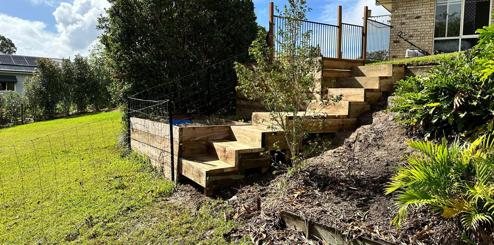 Timber Steps and Retaining Wall Installation by Brett Handyman – Noosa QLD Timber retaining wall with outdoor staircase built on a sloped backyard in Noosa QLD